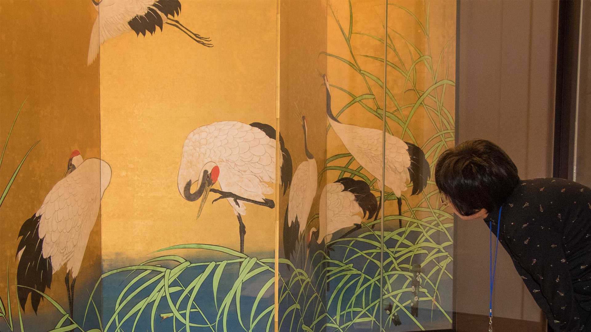 A visitor peering closely to a panel artwork 